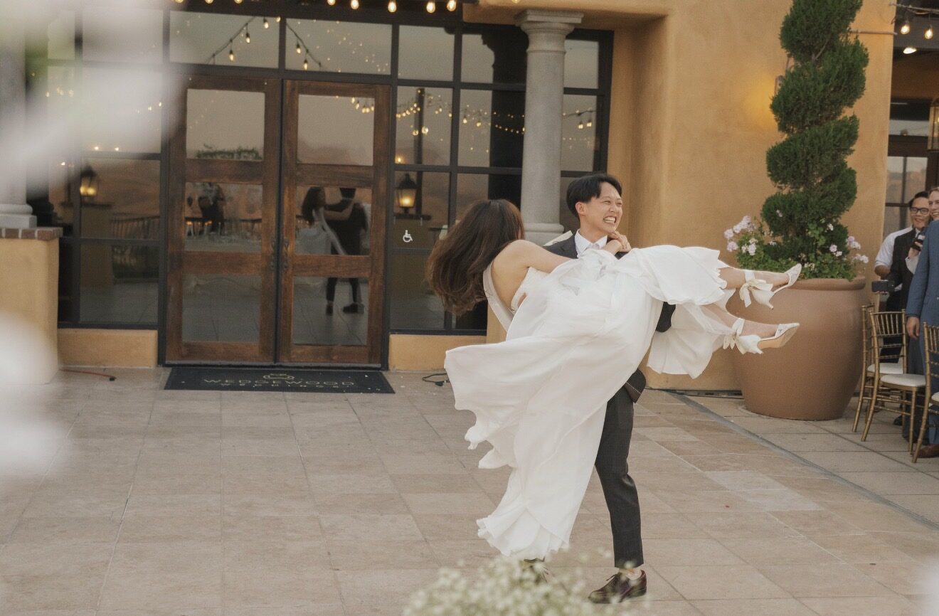 Groom joyfully carrying his bride during their wedding dance